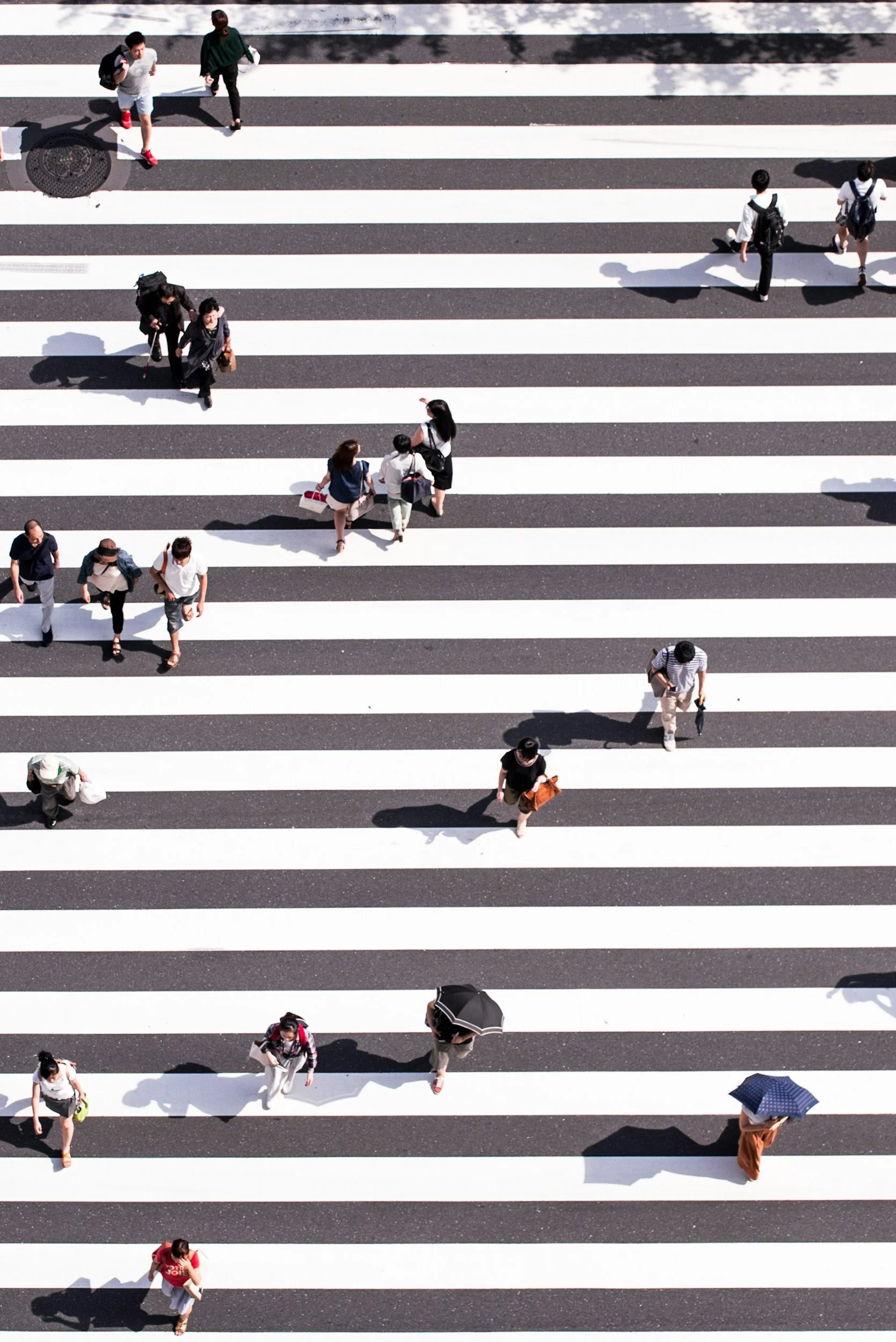 Overhead view of pedestrians crossing a striped crosswalk.